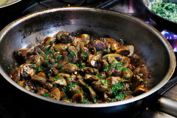 saute mushrooms and onions in a frying pan on firel