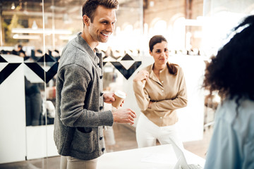 Obraz premium Cheerful young man chatting with female colleagues at work