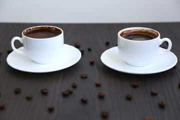 Morning coffee, spilled coffee beans, two cups of coffee, wooden table,