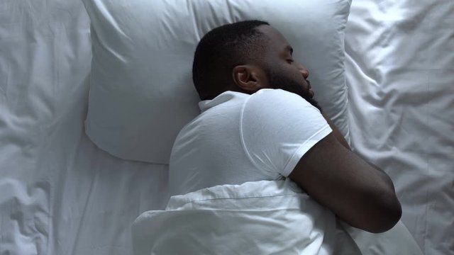 African american bachelor sleeping in his bed, crisis in relationships, top view