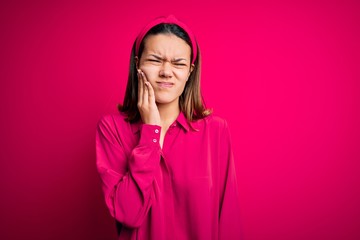 Young beautiful brunette girl wearing casual shirt standing over isolated pink background touching mouth with hand with painful expression because of toothache or dental illness on teeth. Dentist