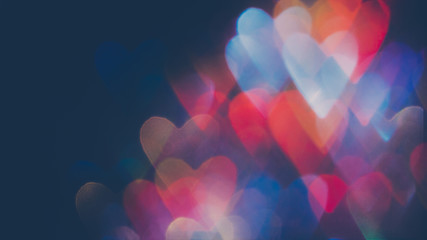 Romantic background. Valentine day. Multicolor bokeh hearts shape lights on dark.