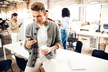 Obraz premium Amazed young man using cellphone at work