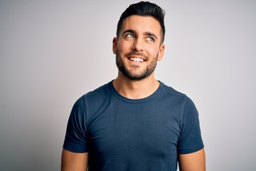 Obraz premium Young handsome man wearing casual t-shirt standing over isolated white background looking away to side with smile on face, natural expression. Laughing confident.