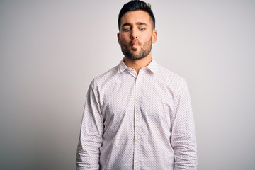 Young handsome man wearing elegant shirt standing over isolated white background making fish face with lips, crazy and comical gesture. Funny expression.