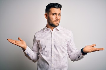 Young handsome man wearing elegant shirt standing over isolated white background clueless and...