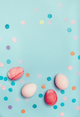 Fototapeta na wymiar Cute light blue background with pink eggs and confetti.