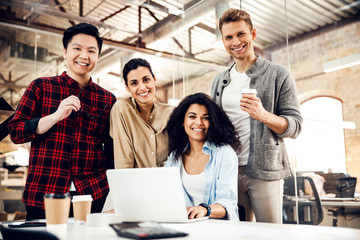 Joyful business people using laptop in modern office