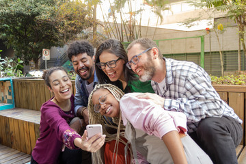 Brazilian group of young adult friends having a break for a selfie photograph all together in the outdoor. Cheerful, happy youth moment.