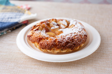 A closeup view of a plate of almond tart, in a restaurant or kitchen setting.