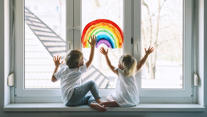 Little children on background of painting rainbow on window