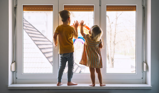 Little children on background of painting rainbow on window