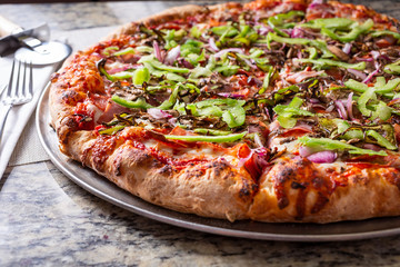 A view of a veggie and meat pizza pie in a restaurant or kitchen setting.