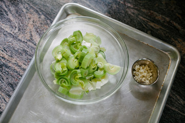 Freshly cut leeks in a glass bowl on marble surface