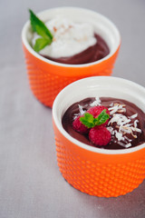 Chocolate mousse dessert served in bright orange  ceramic cups