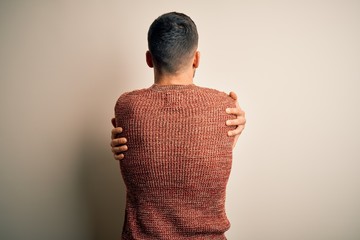 Young handsome man wearing casual sweater standing over isolated white background Hugging oneself happy and positive from backwards. Self love and self care