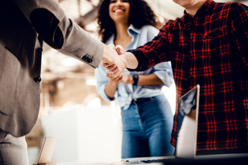 Business partners shaking hands while lady smiling