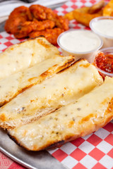 A closeup view of a sampler plate, featuring garlic cheese bread and buffalo wings, in a restaurant or kitchen setting.