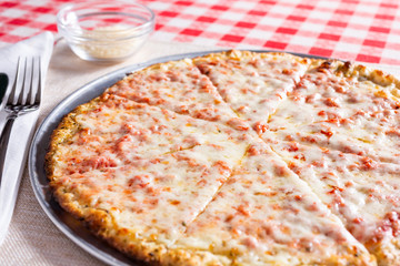 A view of a rustic cheese pizza, in a restaurant or kitchen setting.
