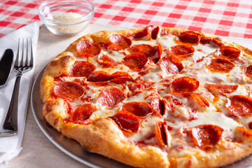 A view of a pepperoni pizza, in a restaurant or kitchen setting.