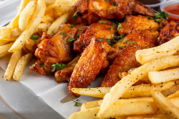 A view of an appetizer plate featuring buffalo wings and french fries, in a restaurant or kitchen setting.