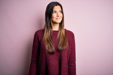 Young beautiful girl wearing casual sweater over isolated pink background smiling looking to the side and staring away thinking.