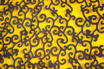 Full frame background of traditional decorative black wrought-iron pattern on bright yellow painted wall