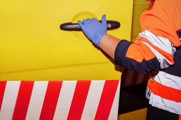Fototapeta premium Night scene of an unrecognizable Paramedic at work, opening Ambulance door, ready to assist an emergency .