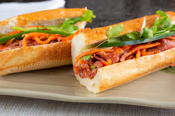 A closeup view of barbecue pork banh mi Vietnamese sandwiches, in a restaurant or kitchen setting.