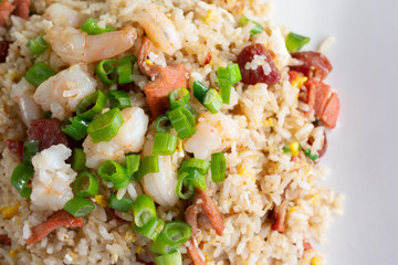 A top down closeup view of a plate of shrimp fried rice, in a restaurant or kitchen setting.