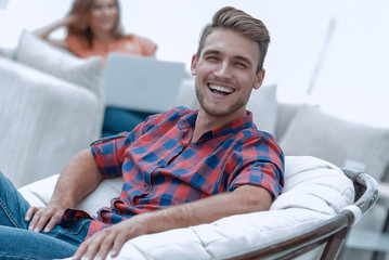 happy young man sitting in a big chair on blurred background