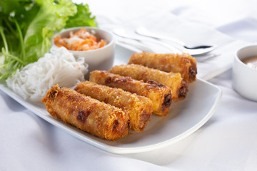 A view of an appetizer plate of egg rolls, in a restaurant or kitchen setting.