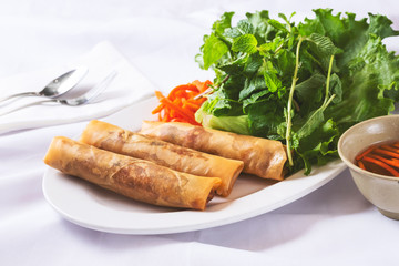 A view of a plate of egg rolls, in a restaurant or kitchen setting.