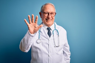 Senior grey haired doctor man wearing stethoscope and medical coat over blue background showing and pointing up with fingers number five while smiling confident and happy.