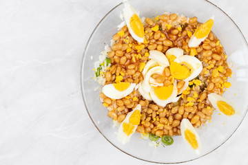 Cooked beans with rice salad served in the bowl decorated with eggs