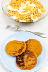 Cooked beans salad with fishcakes and bread served on the table