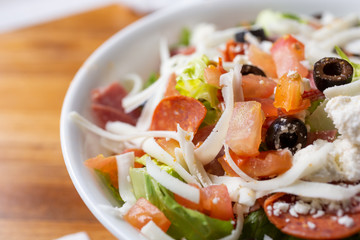 A closeup view of an antipasto salad, cut off on the right side of the frame, in a restaurant or kitchen setting.