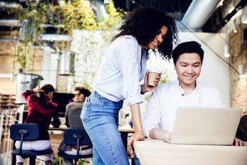 Cheerful young man and woman using laptop at work