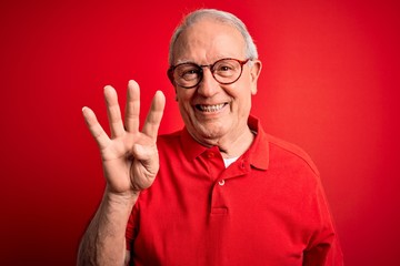 Grey haired senior man wearing glasses and casual t-shirt over red background showing and pointing up with fingers number four while smiling confident and happy.