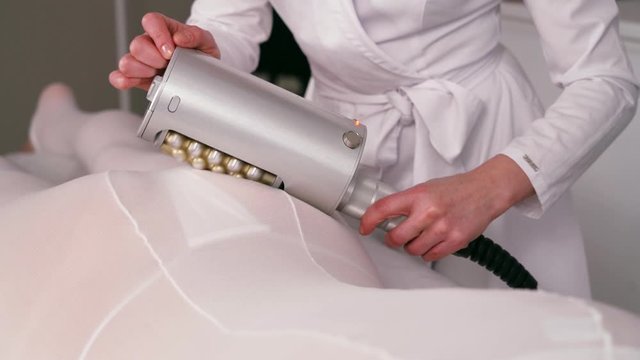 Masseur makes apparatus anti-cellulite massage in the cosmetology clinic