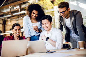 Joyful young people using laptop at work