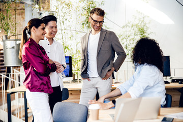 Joyful multiracial workers chatting and laughing in office