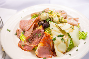 A view of a plate of antipasto salad, in a restaurant or kitchen setting.