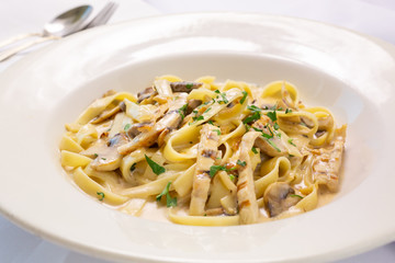 A view of a plate of fettuccine noodles with chicken, in a restaurant or kitchen setting.