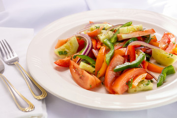A view of a plate of Italian tomato salad, in a restaurant or kitchen setting.