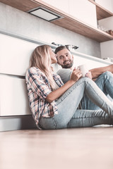 Fototapeta premium young couple drinking coffee sitting on the kitchen floor