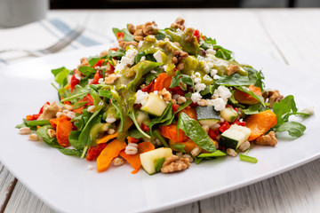 A view of a Mediterranean spinach and roasted veggie garden salad, in a restaurant or kitchen setting.