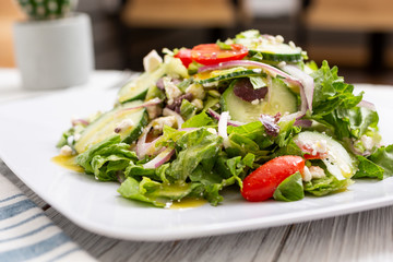 A view of a Greek garden salad, in a restaurant or kitchen setting.