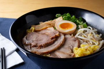 A closeup view of a bowl of Japanese miso ramen soup, in a restaurant or kitchen setting.