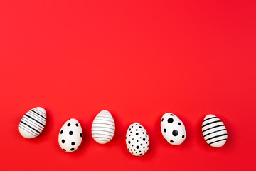 Different graphic hand-painted eggs on trendy coral background. Easter concept. Place for text.